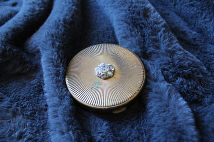 Round gold colour compact with clear jewel detail